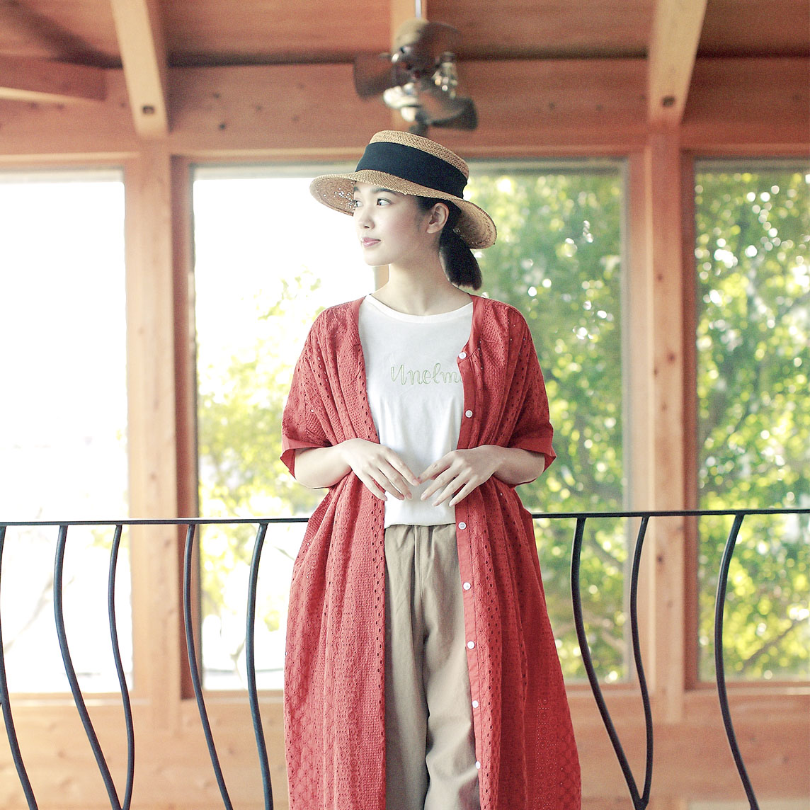 赤いロングカーディガンと麦わら帽子の女性モデルの写真