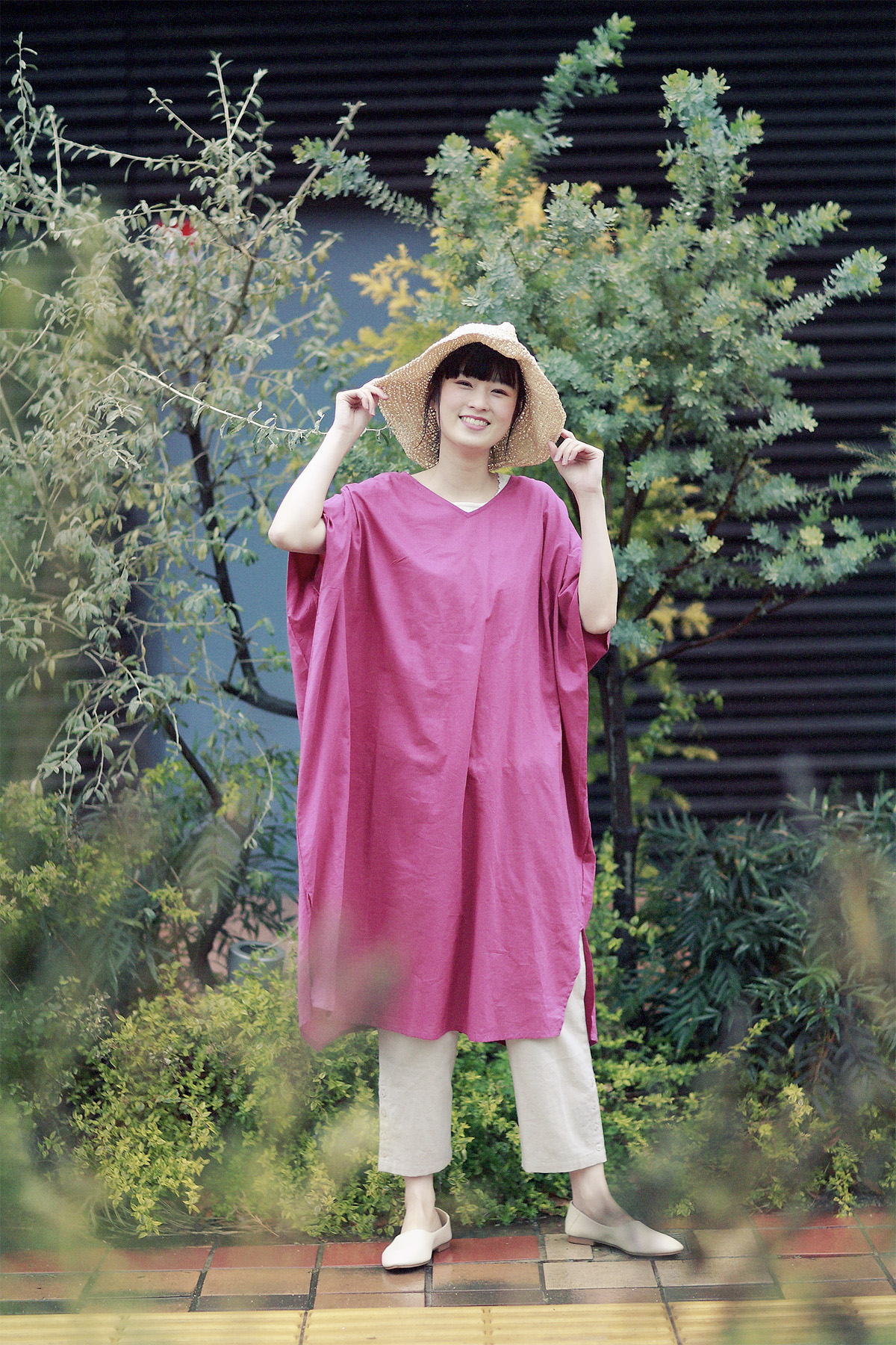 ピンクのワンピースに麦わら帽子のコーディネートの女性モデル写真