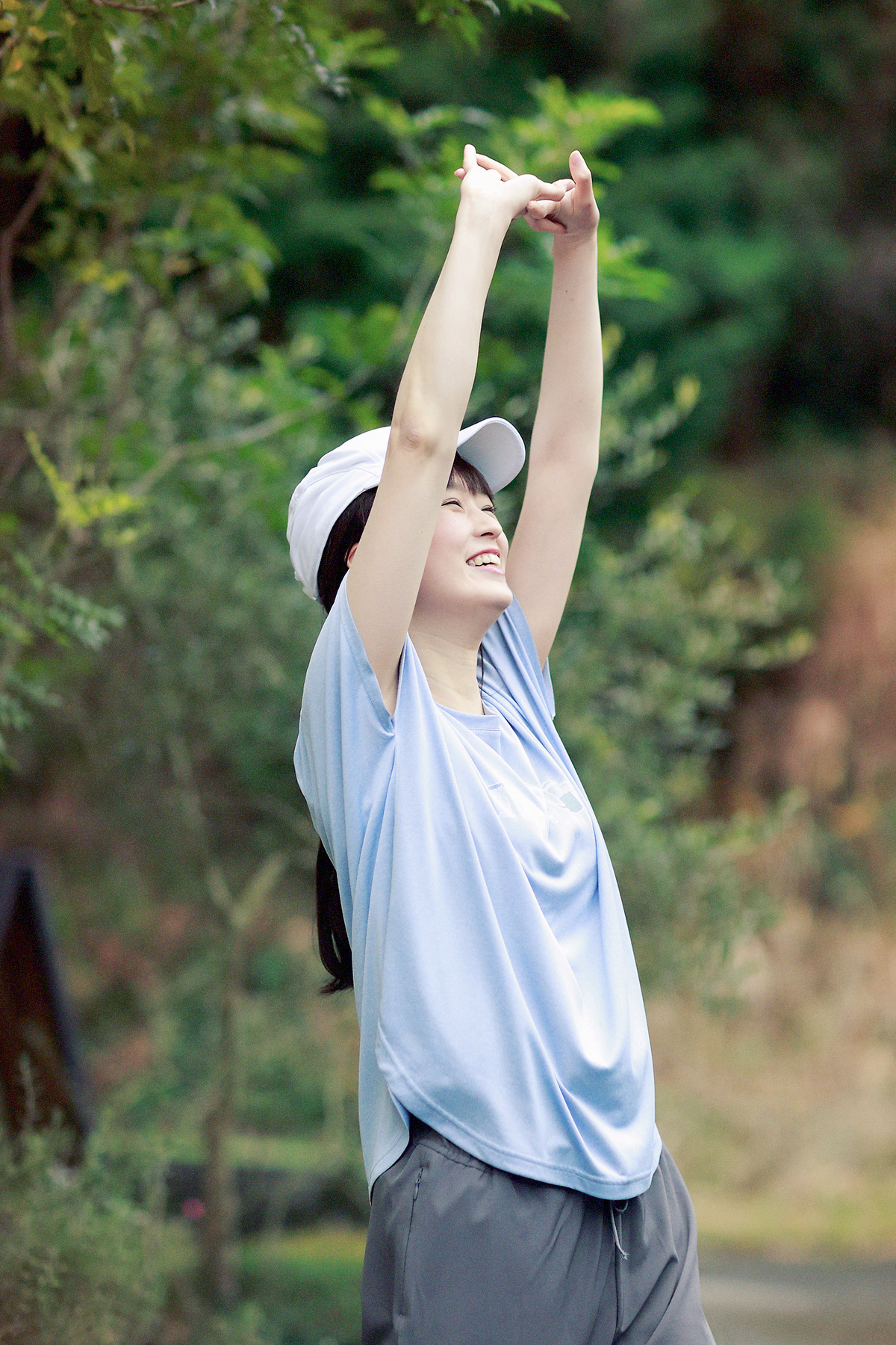  Tシャツで伸びをする女性モデルの写真